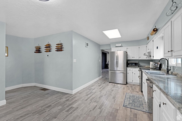 275 E 1st S, Preston, ID 83263 - kitchen with light wood finished floors, stainless steel appliances, a sink, baseboards, and under cabinet range hood