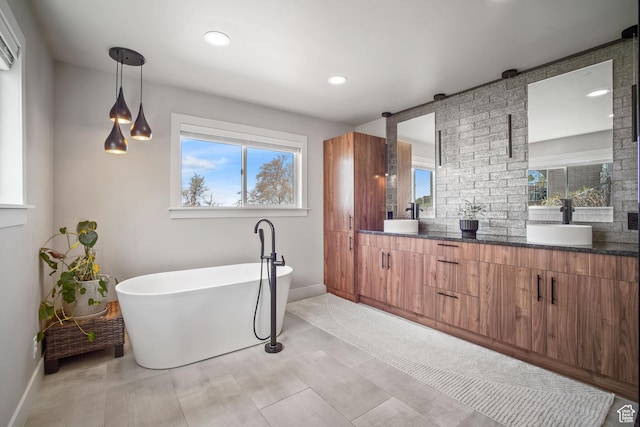 full bathroom featuring a freestanding bath, double vanity, baseboards, and a sink