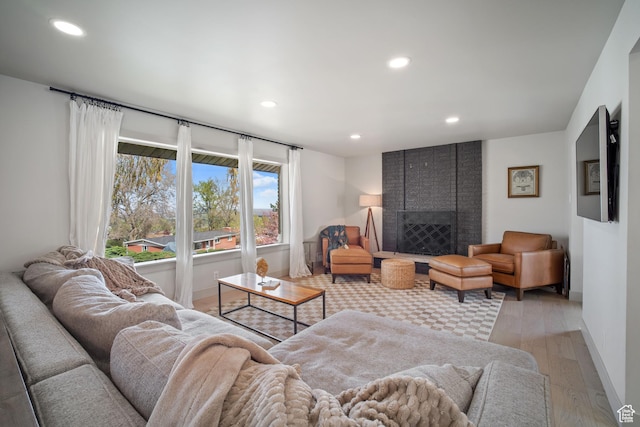 living room featuring light wood-style flooring, baseboards, recessed lighting, and a fireplace