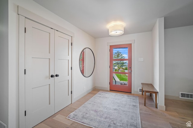 foyer entrance featuring light wood-style flooring, visible vents, and baseboards