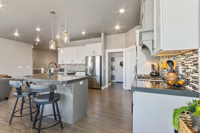 6982 W Majestic View Ln S, Herriman, UT 84096 - kitchen with a sink, stainless steel fridge, a center island with sink, backsplash, and a breakfast bar