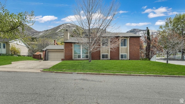 view of front of house with a front lawn, concrete driveway, brick siding, a mountain view, and a garage