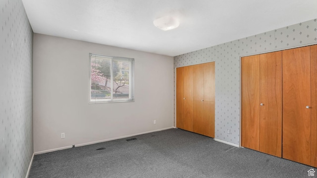 unfurnished bedroom with visible vents, wallpapered walls, baseboards, and carpet flooring