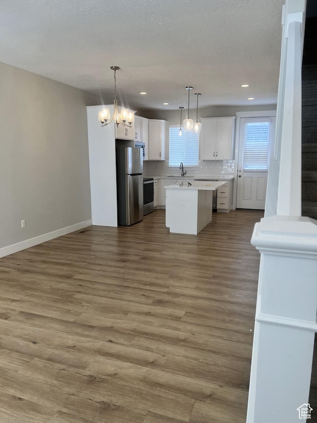 kitchen featuring a sink, stainless steel appliances, a healthy amount of sunlight, white cabinetry, and light countertops