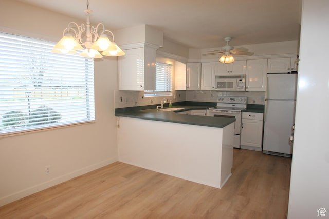 1974 W 5200 S, Roy, UT 84067 - kitchen with white appliances, dark countertops, a peninsula, a chandelier, and plenty of natural light