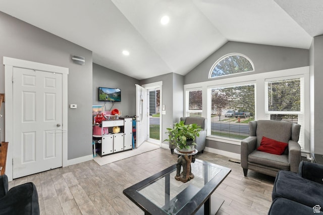 living room featuring light wood-style floors, vaulted ceiling, and baseboards
