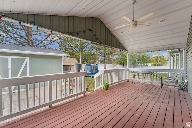 wooden deck featuring ceiling fan, fence, and a trampoline