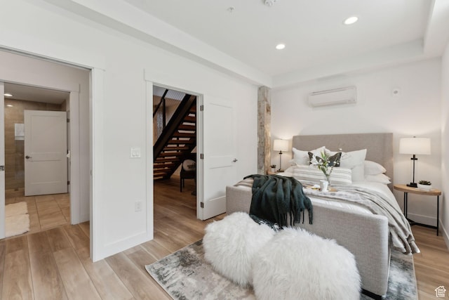 bedroom with a wall mounted air conditioner, light wood-style flooring, recessed lighting, and baseboards