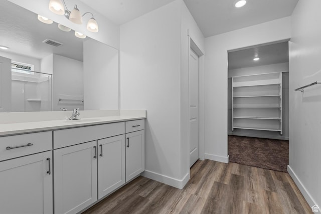 bathroom featuring wood finished floors, visible vents, vanity, and baseboards