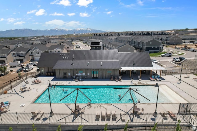 community pool with a patio area, fence, and a residential view