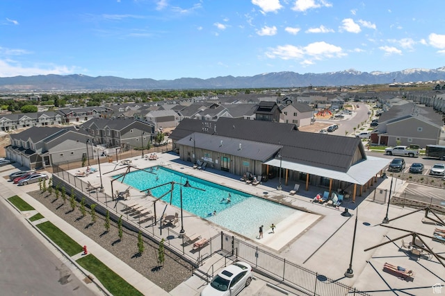 pool with a patio, a mountain view, fence, and a residential view