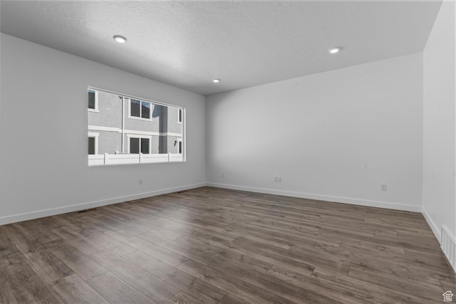 unfurnished room with recessed lighting, baseboards, visible vents, and dark wood-style floors