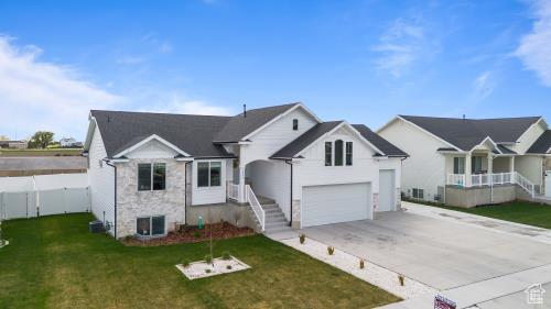 1065 W 275 S, Tremonton, UT 84337 - ranch-style house with a garage, concrete driveway, stone siding, fence, and a front yard