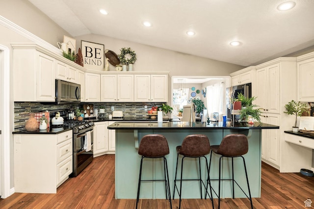 kitchen with dark countertops, decorative backsplash, double oven range, a kitchen bar, and lofted ceiling