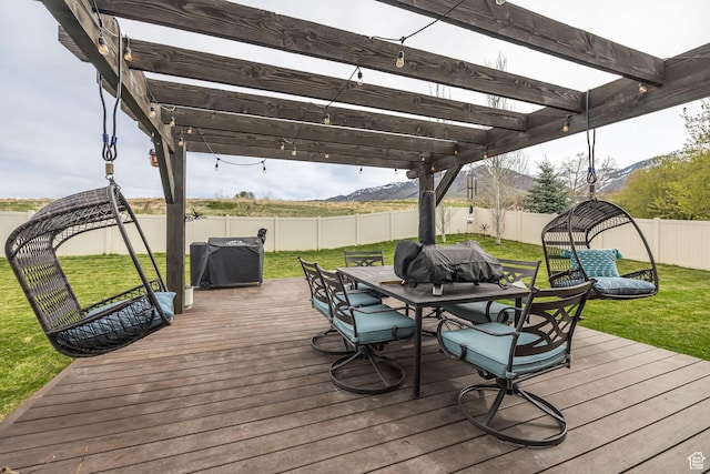 wooden deck featuring a pergola, a fenced backyard, outdoor dining space, a lawn, and a mountain view