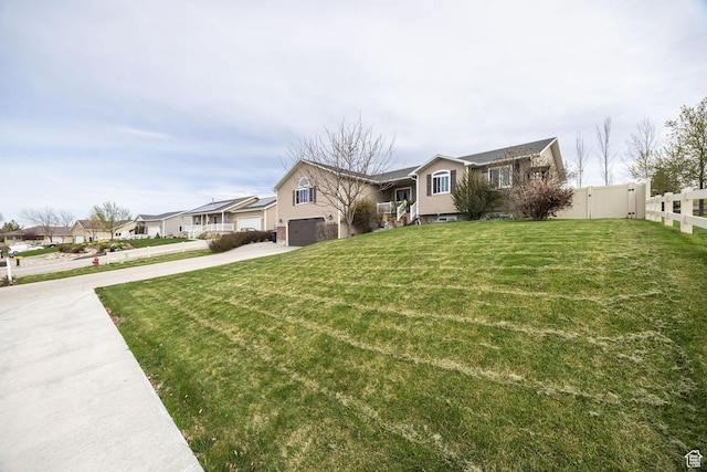 view of front of property with fence, a residential view, driveway, a front yard, and a garage