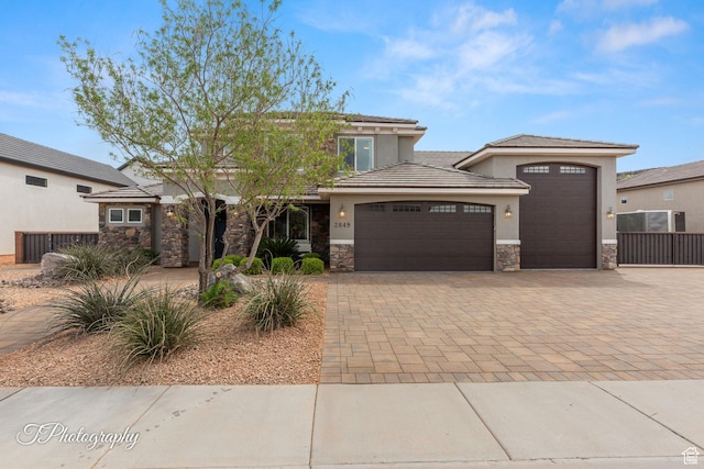prairie-style home with an attached garage, stone siding, stucco siding, and driveway