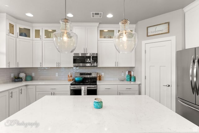 kitchen with tasteful backsplash, glass insert cabinets, stainless steel appliances, white cabinets, and visible vents