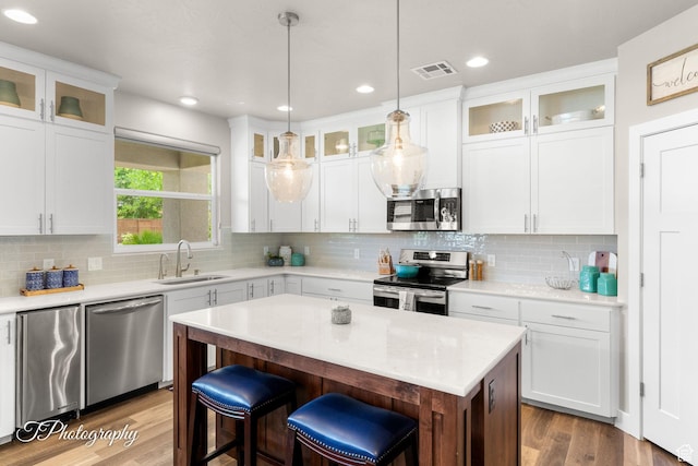 kitchen featuring a center island, a sink, visible vents, wood finished floors, and appliances with stainless steel finishes