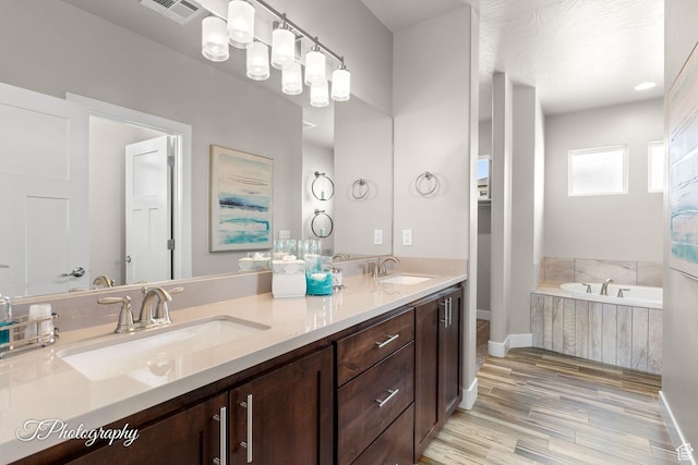 full bathroom with baseboards, wood finished floors, visible vents, and a sink