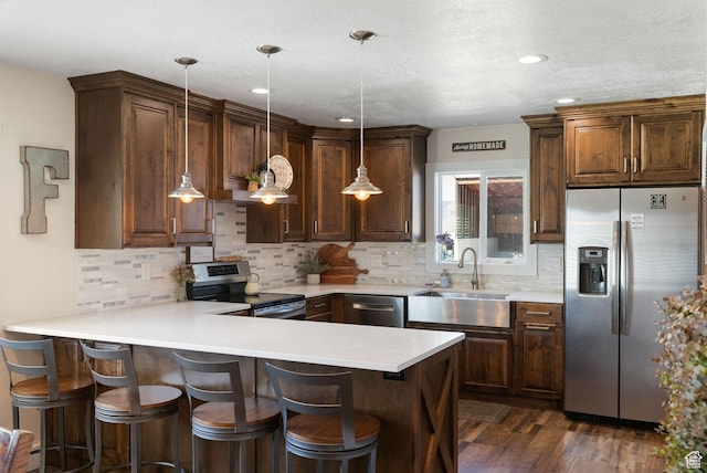 975 N 1400 W, Preston, ID 83263 - kitchen with stainless steel appliances, a sink, decorative backsplash, a peninsula, and dark wood-style flooring