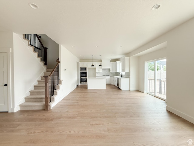 569 W 2030 N, Tooele, UT 84074 - unfurnished living room with stairway, light wood-type flooring, and recessed lighting