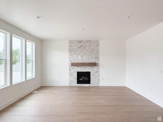 569 W 2030 N, Tooele, UT 84074 - unfurnished living room with light wood-type flooring, a stone fireplace, and recessed lighting