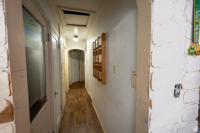 hallway with attic access, arched walkways, and dark wood-type flooring