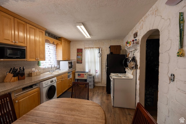 kitchen with wood finished floors, white appliances, a sink, and washer / clothes dryer