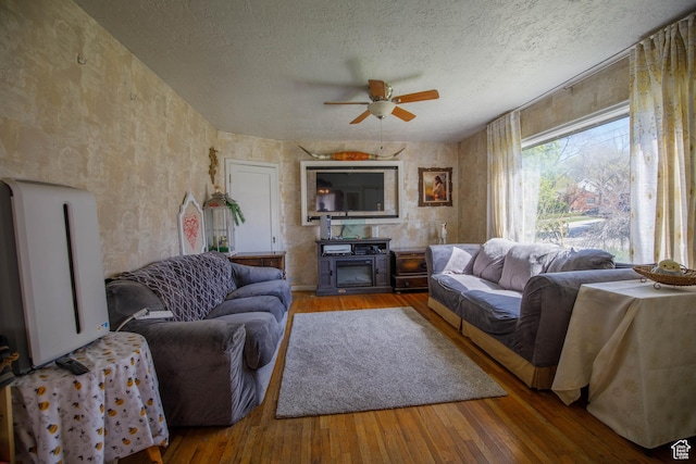 living area featuring a ceiling fan, hardwood / wood-style floors, and a textured ceiling