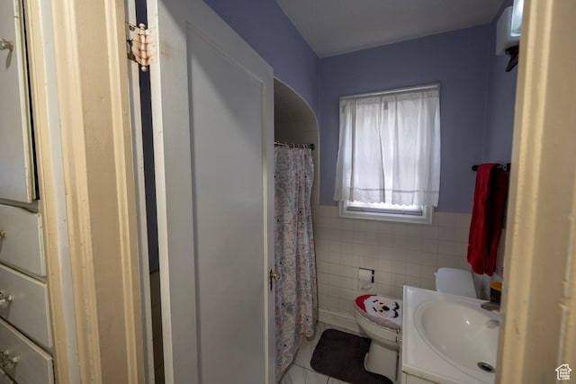 full bathroom with tile patterned floors, a wainscoted wall, toilet, tile walls, and vanity