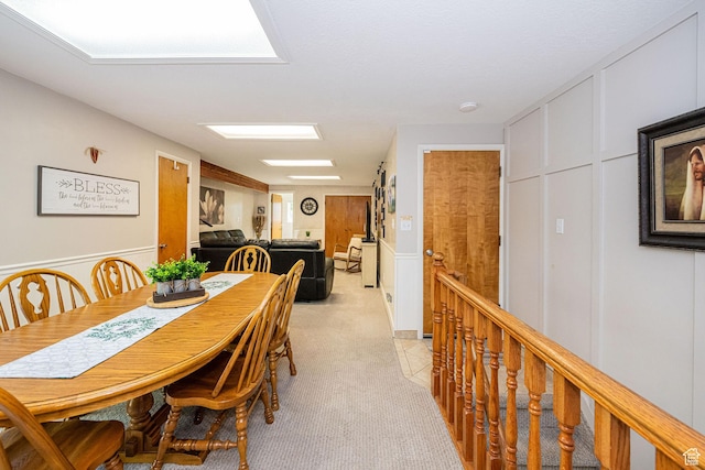 dining area with light carpet and a decorative wall