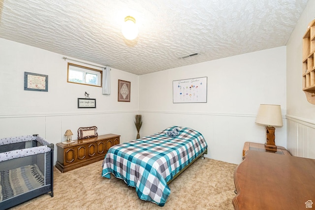 bedroom with a textured ceiling, visible vents, and carpet
