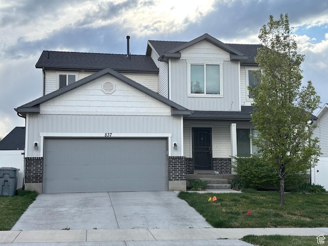 view of front of house featuring a front lawn, driveway, a garage, brick siding, and a shingled roof