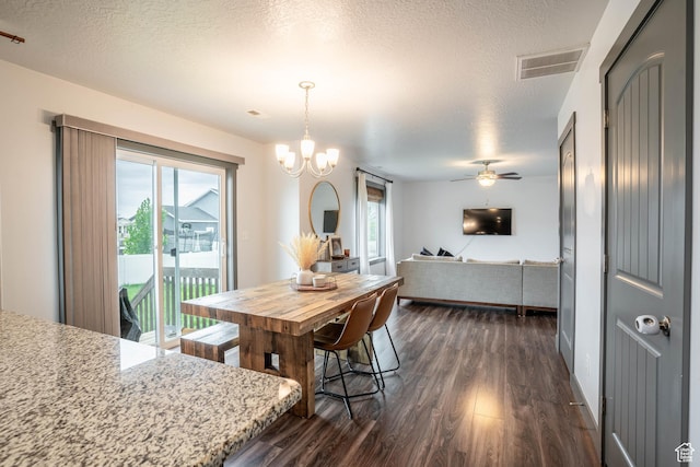 dining space with a textured ceiling, visible vents, dark wood-style flooring, and a healthy amount of sunlight