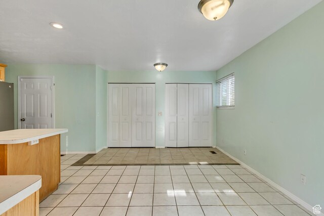 3916 S Hawkeye Dr, West Valley City, UT 84120 - unfurnished bedroom with baseboards, multiple closets, and light tile patterned floors