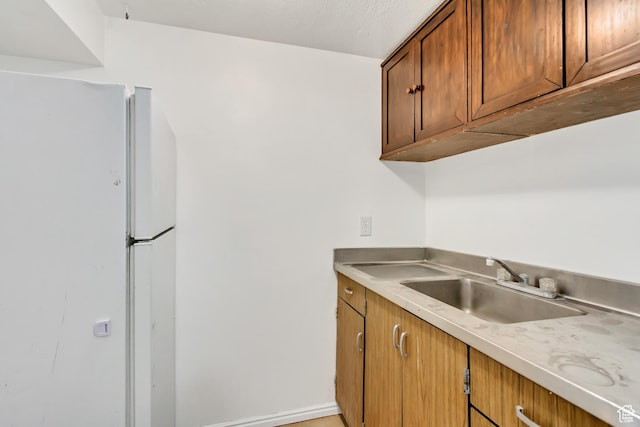3916 S Hawkeye Dr, West Valley City, UT 84120 - kitchen featuring light countertops, freestanding refrigerator, a sink, and brown cabinets
