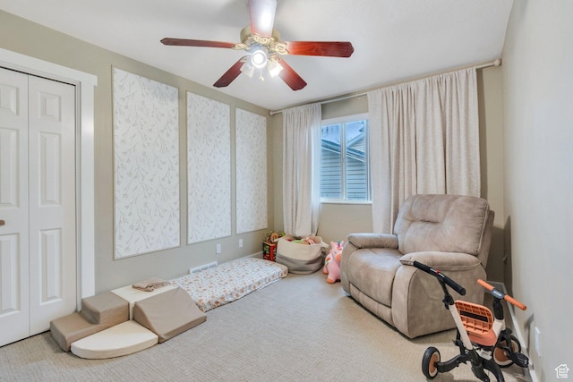 sitting room with carpet floors, visible vents, and a ceiling fan