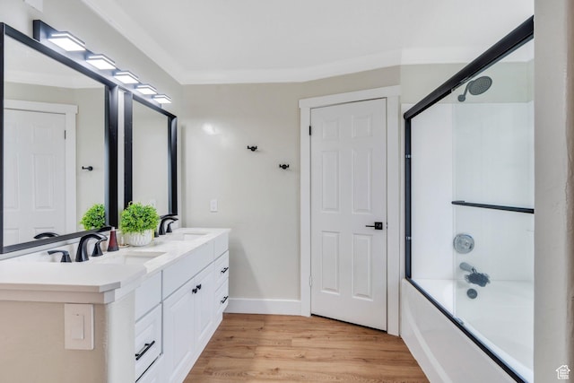 bathroom featuring bathtub / shower combination, wood finished floors, a sink, and double vanity