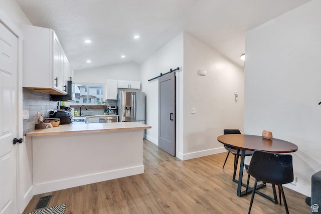 kitchen with a peninsula, tasteful backsplash, a barn door, light countertops, and appliances with stainless steel finishes