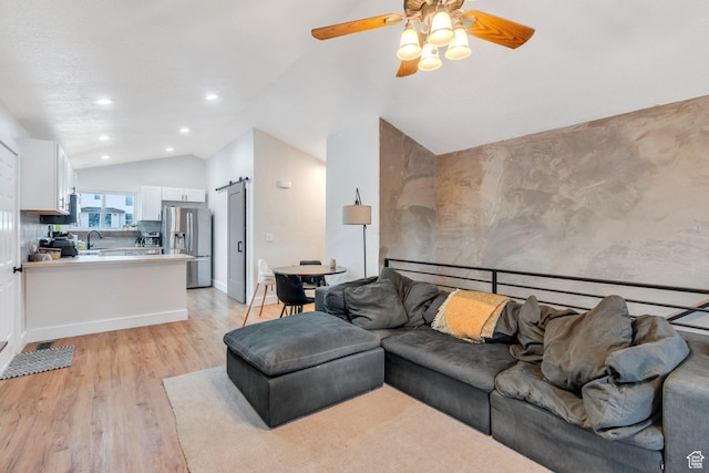 living area featuring a barn door, light wood-type flooring, ceiling fan, lofted ceiling, and recessed lighting
