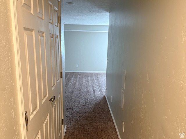 corridor with carpet floors, a textured ceiling, and baseboards