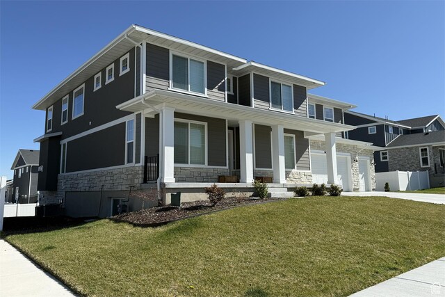 6129 W Coulee Ln, West Jordan, UT 84081 - view of front of home featuring driveway, a porch, stone siding, and a front yard