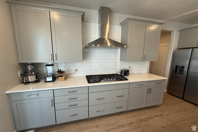 6129 W Coulee Ln, West Jordan, UT 84081 - kitchen featuring gray cabinets, backsplash, light wood-style floors, wall chimney range hood, and appliances with stainless steel finishes
