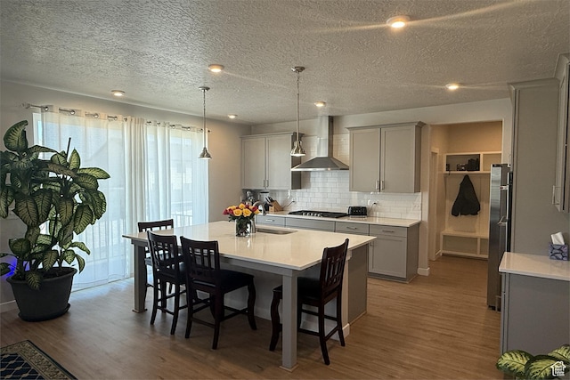 6129 W Coulee Ln, West Jordan, UT 84081 - kitchen featuring wood finished floors, wall chimney range hood, gray cabinets, and a wealth of natural light