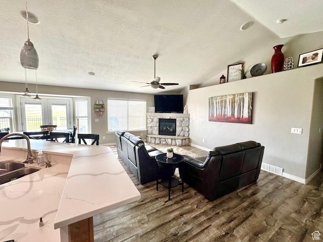 8675 N Franklin Dr E, Eagle Mountain, UT 84005 - living room with a stone fireplace, a textured ceiling, ceiling fan, dark wood-style flooring, and visible vents