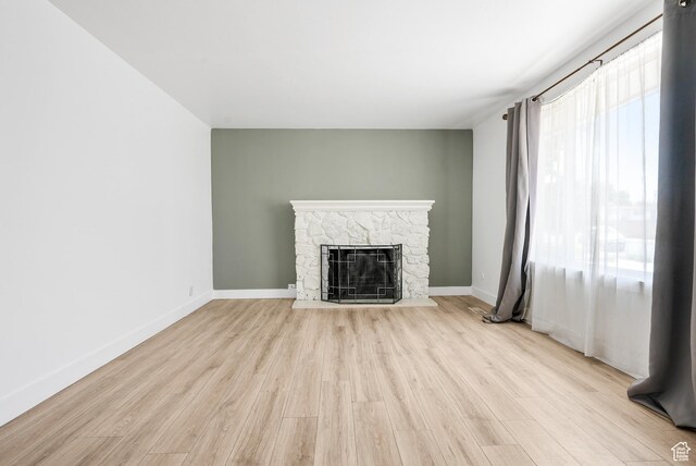 4217 S Hopi Dr, West Valley City, UT 84119 - unfurnished living room featuring a stone fireplace, wood finished floors, and baseboards