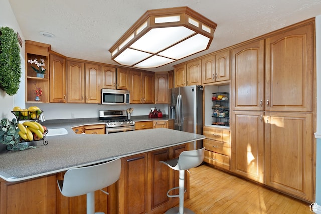 1380 S 980 E, Spanish Fork, UT 84660 - kitchen featuring stainless steel appliances, a peninsula, a kitchen breakfast bar, light wood-style floors, and open shelves