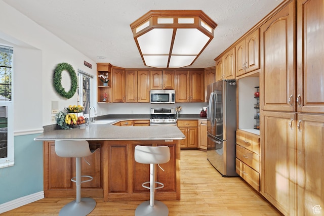 1380 S 980 E, Spanish Fork, UT 84660 - kitchen featuring stainless steel appliances, a peninsula, a sink, light wood-type flooring, and a kitchen bar