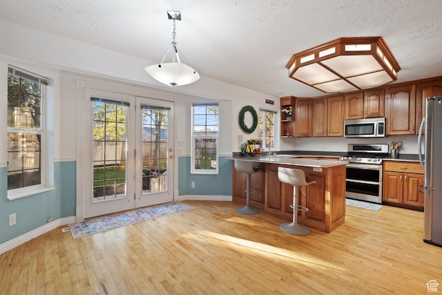 1380 S 980 E, Spanish Fork, UT 84660 - kitchen featuring light wood-style floors, brown cabinetry, baseboards, and stainless steel appliances